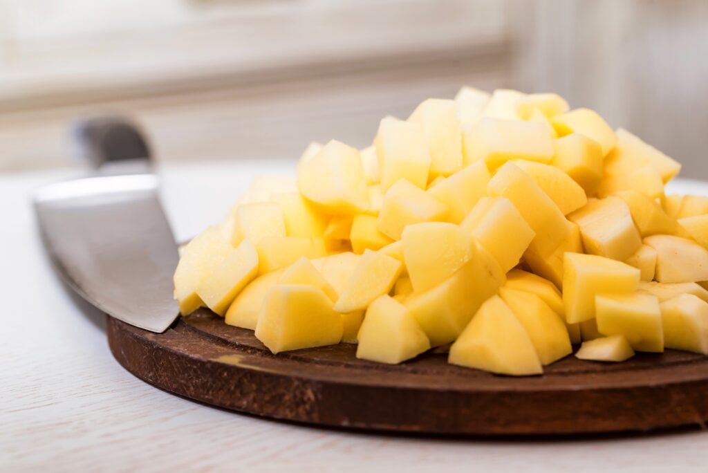 Pile of potato cut in pieces on wooden board