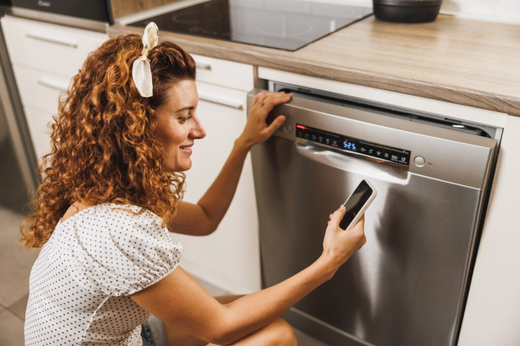 Who Makes Best Dishwasher - Woman Using Mobile App To Control Dishwasher
