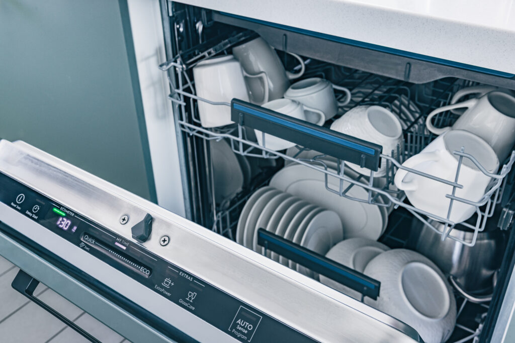Dishwasher is full of clean dishes. The dishwasher is white and silver